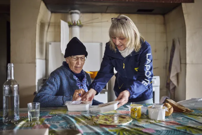 Postière apportant le repas à une personne âgée