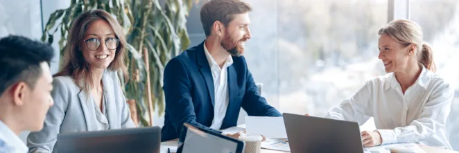 2 hommes et 2 femmes assis à une table conversent dans une entreprise